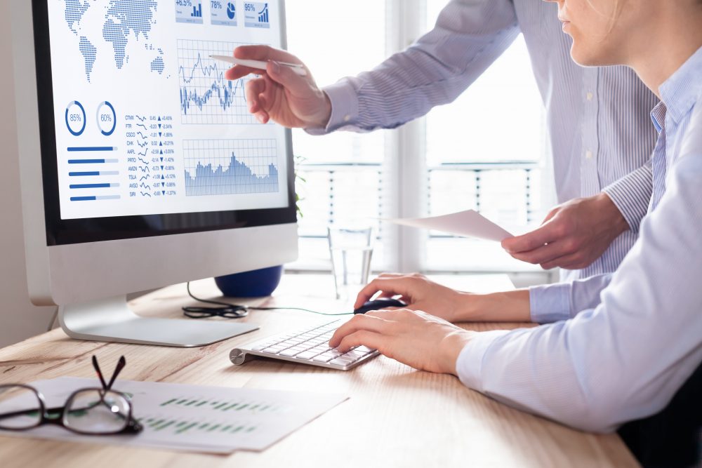 Two people analyzing stock market investment strategy with key performance indicator on financial dashboard and business intelligence on computer