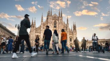 Blurred people, tourists and commuters at sunset crossing Duomo Square in Milano.