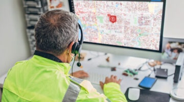 A person at a control center, managing an emergency situation using E911 and mass notification technology.