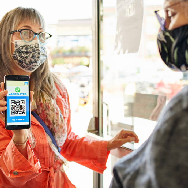 woman showing vaccine info via phone app at an office security entrance point