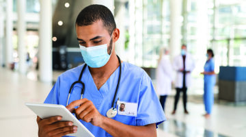 Mixed Race Nurse Using Digital Tablet At Hospital