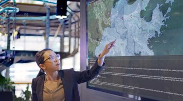 Woman point to and presenting critical event data shown on a a display.
