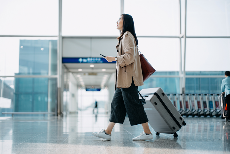 Woman walking through an airport with a phone in her hand