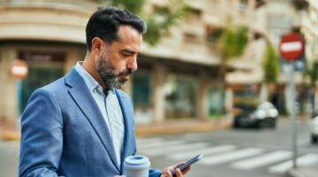 Middle Age Businessman Using Smartphone And Drinking Coffee At The City.