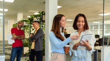 Two Young Diverse Businesswoman Using A Digital Tablet In The Office